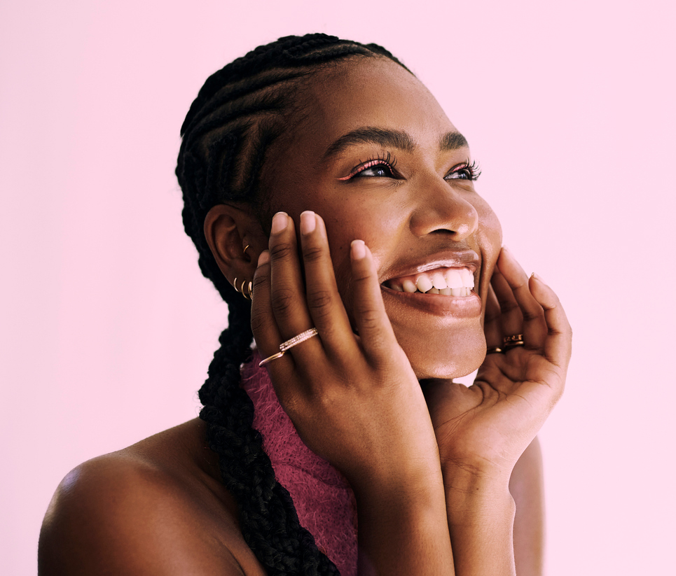 A person smiling joyfully against a pink background.