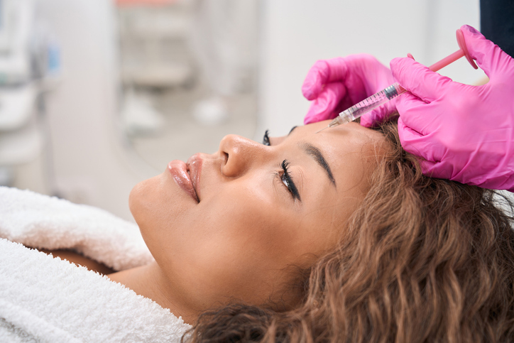 A woman receiving a cosmetic injection in a clinic setting.