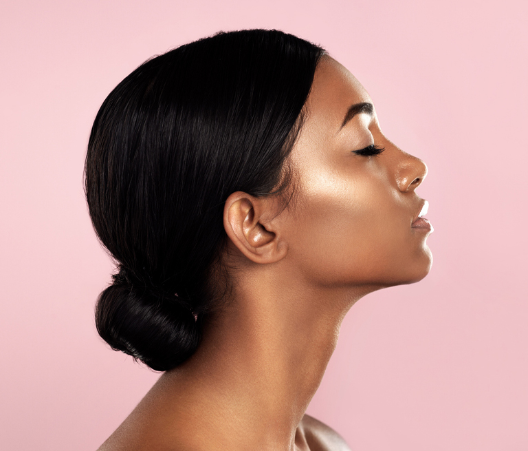 Profile of a woman with smooth skin against a pink background.