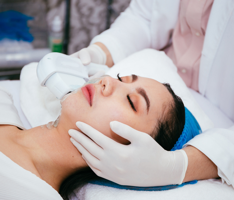 A woman receiving a skincare treatment with a device, lying down in a spa setting.