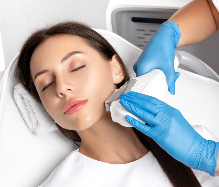 Woman receiving a facial treatment with a device operated by gloved hands.