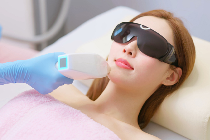Woman receiving laser skin treatment wearing protective goggles.