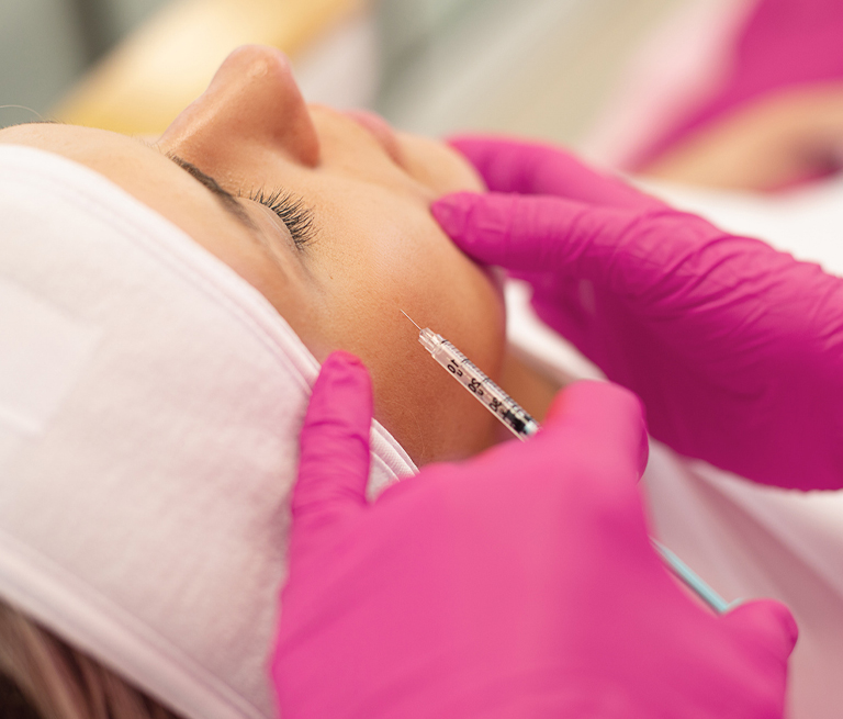 A person receiving facial injection with pink gloves.