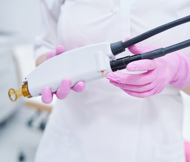 Person in pink gloves holding a medical device in a clinic setting.