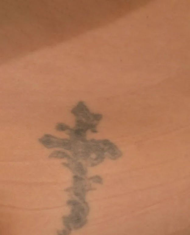 Tattoo of a cross with floral details on skin.