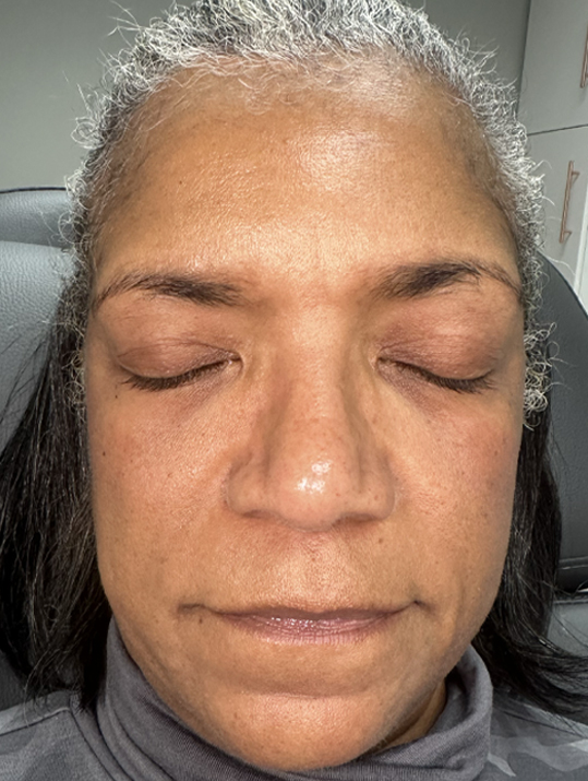 A person with eyes closed, lying back on a chair, wearing a gray turtleneck.