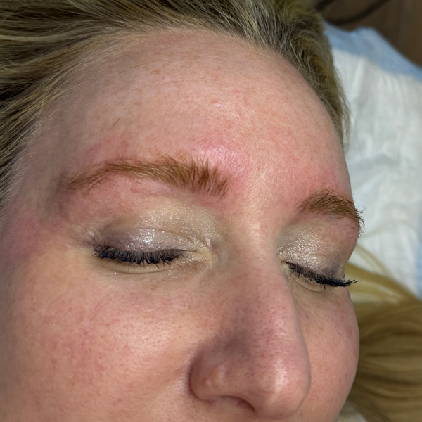 Woman with freshly styled eyebrows lying down with closed eyes.