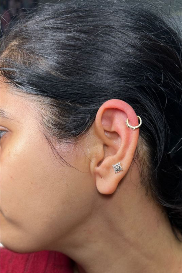 Close-up of a woman's ear with a hoop and stud earrings.